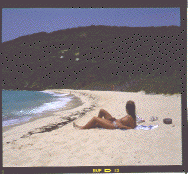 [Photo of a couple lying on a beach with a long empty stretch of sand in the background.]